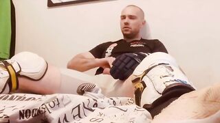 Hockey player jacking off in shinpads and cleats with his glove covered hands